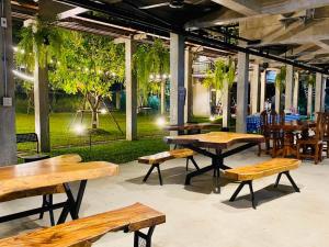 a group of tables and benches in a restaurant at Tree House Home Stay บ้านต้นไม้โฮมสเตย์อุทัยธานี in Uthai Thani
