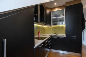 a kitchen with black cabinets and a sink at Central & Typical Lisboa by GT House in Lisbon