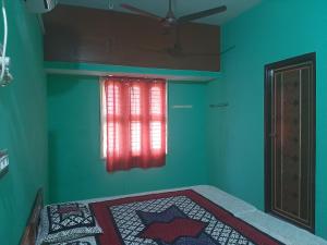 a bedroom with a bed with a red window at Padmavathi Home Stay in Chidambaram