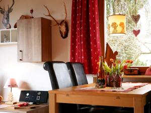 mesa de comedor con sillas y cortina roja en Haus Jurisch, en Urberg