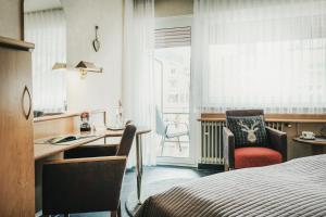 Habitación de hotel con escritorio, cama y ventana en Hotel Koch, en Bad Liebenzell