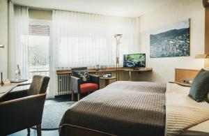 バート・リーベンツェルにあるHotel Kochのベッド、デスク、椅子が備わるホテルルームです。