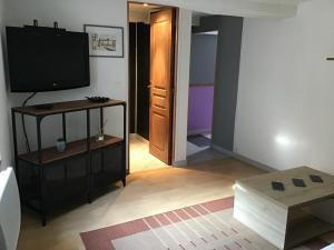 ein Wohnzimmer mit einem Flachbild-TV und einem Tisch in der Unterkunft Maison calme et fonctionnelle in Mousseaux-sur-Seine