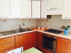 a kitchen with white cabinets and a sink and a stove at LES PETITES MAISONS maison orange in Procida