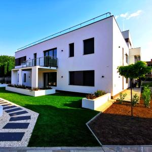 a white house with a green lawn in front of it at LaVida Deluxe villa Hajdúszoboszló in Hajdúszoboszló