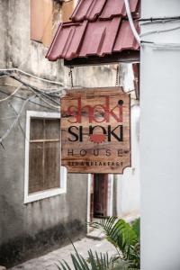 ein Schild für ein Geschäft mit einem Schild für ein Gebäude in der Unterkunft Shoki Shoki House Stone Town in Zanzibar City