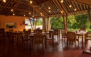 a restaurant with wooden tables and chairs in a room at Big Tree Cottages in Beadonābād