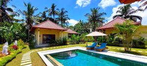 a villa with a swimming pool in front of a house at TAMAN EDEN COTTAGE in Ubud