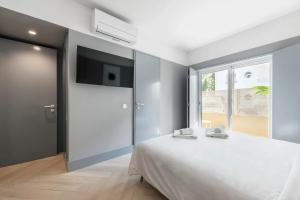 a bedroom with a white bed and a flat screen tv at Jardim Suites by Olala Homes in Cascais