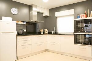a kitchen with white cabinets and a clock on the wall at Modernes Haus mit spektakulärem Meerblick und Pool in Vale Furado