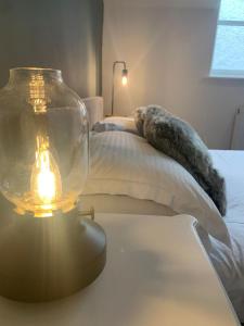 a glass jar on a table next to a bed at Biskey Howe Central - FREE off-site Health Club access with Pool, Sauna, Steam Room & Gym in Bowness-on-Windermere