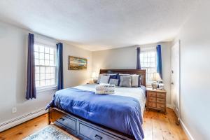 1 dormitorio con 1 cama con edredón azul y 2 ventanas en Cozy Charming Cottage, en Brewster