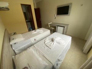 a room with three beds with white sheets and a television at GRAN PARADA HOTEL in Castanhal