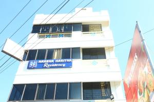 a white building with a blue sign on it at Harsha Haritha Residency in Cuddalore