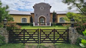 a fence in front of a house with a clock tower at HERMOSA CASA con 4000mts de PARQUE en las SIERRAS DE CORDOBA in José de la Quintana