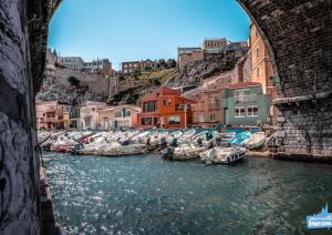 a group of boats docked in the water under a bridge at Une calanque au coeur de la ville in Marseille