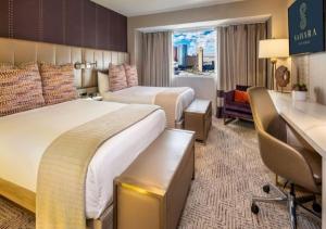 a hotel room with two beds and a desk at SAHARA Las Vegas in Las Vegas