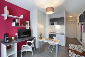 a living room with a table and a kitchen at Résidence Nemea Aix Campus 2 in Aix-en-Provence
