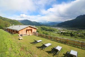 a group of chairs sitting on a hill with a cabin at Maso al Sole Agriturismo in Civezzano