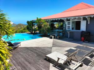 a house with a deck and a swimming pool at LA MAISON BLEUE - Les Hauts de la Baie in Terre-de-Bas