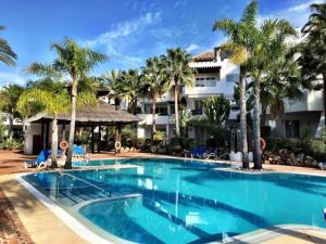 een zwembad in een resort met palmbomen bij Beachside Luxury 2 bedroom apartment, Puerto Banus in Marbella
