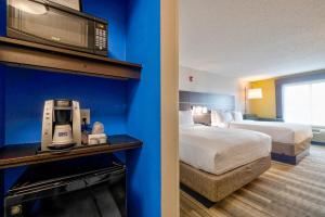 a hotel room with a bedroom with a bed and a room with a bed istg at Holiday Inn Express Hotel & Suites Kansas City - Grandview, an IHG Hotel in Grandview