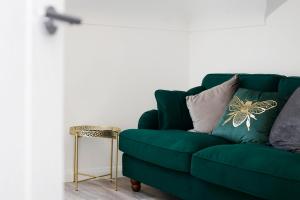 a green couch with pillows and a side table at Nightingale - Perfect location close to the Beach - Free Parking in Bournemouth