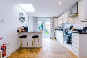 a kitchen with two stools in a kitchen with a clock on the wall at Pristine 2-bed house in Chester by 53 Degrees Property, ideal for Families & Small groups, Great Location - Sleeps 6 in Hough Green