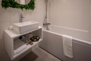 a white bathroom with a sink and a tub at Senhora da Rosa, Tradition & Nature Hotel in Ponta Delgada