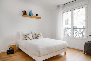a white bedroom with a bed and a window at Edgar Suites Châtillon in Châtillon