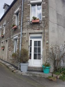 un edificio de ladrillo con una puerta blanca y dos macetas en Lecerf en Condé-sur-Noireau