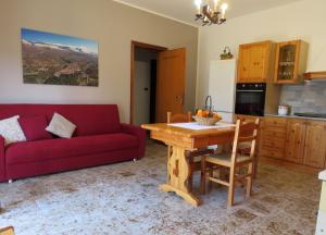 sala de estar con sofá rojo y mesa de madera en Il Canto degli Uccelli en Roccamorice