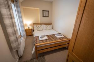 een kleine slaapkamer met een bed met twee schoenen erop bij Cliff Walk Cottage in Arbroath