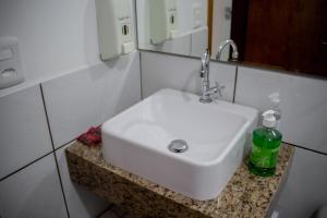 - un lavabo dans la salle de bains avec une bouteille verte sur un comptoir dans l'établissement Pousada Oma Helga, à Pomerode