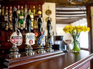 a bar with bottles of beer sitting on a counter at The White Horse Hotel and Luxury Shepherds Huts in Eye