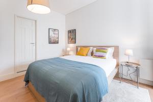 een witte slaapkamer met een groot bed met kleurrijke kussens bij GuestReady - Costa Cabral Guesthouse Room 4 in Porto