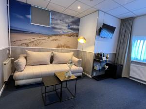 a living room with a couch and a table at SEA YOU Hotel Noordwijk in Noordwijk aan Zee