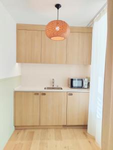 a kitchen with wooden cabinets and a sink at Hôtel Les Grenettes in Sainte-Marie-de-Ré