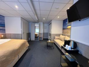 a hotel room with a bed and a flat screen tv at SEA YOU Hotel Noordwijk in Noordwijk aan Zee