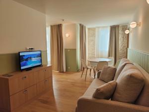 a living room with a couch and a tv at Hôtel Les Grenettes in Sainte-Marie-de-Ré