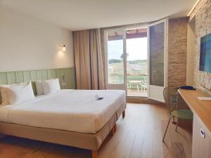 a hotel room with a large bed and a balcony at Hôtel Les Grenettes in Sainte-Marie-de-Ré