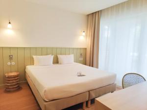 a hotel room with a large bed and a window at Hôtel Les Grenettes in Sainte-Marie-de-Ré