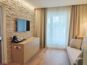 a living room with a tv on a stone wall at Hôtel Les Grenettes in Sainte-Marie-de-Ré