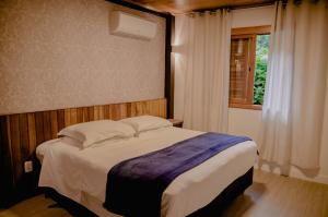 1 dormitorio con 1 cama grande y ventana en Pousada Rosa, en Gramado