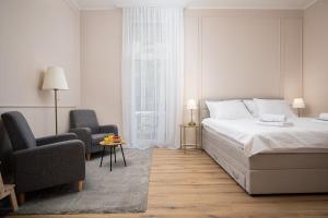 a white bedroom with a bed and two chairs at Grand Munz in Pula