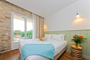 a bedroom with a bed and a large window at Hôtel Les Grenettes in Sainte-Marie-de-Ré