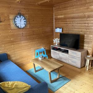 ein Wohnzimmer mit einem TV, einem Tisch und einer Uhr in der Unterkunft Hiška Marjetica in Podčetrtek