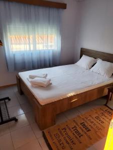 um quarto com uma cama de madeira com lençóis brancos e uma janela em Villa Borisa em Paralía Avdhíron