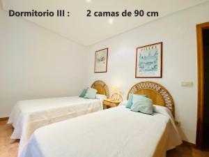 two beds in a room with white walls at Labradores 3 dormitorios in Peñíscola