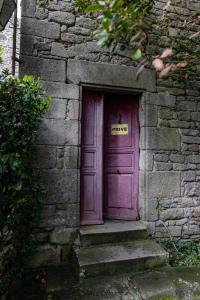 una puerta morada en un edificio de piedra con escalones en joli appartement 2 pers dans les remparts de Guérande, en Guérande
